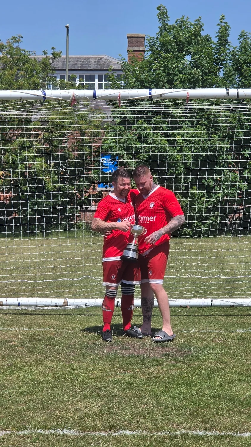 Heron United players holding the trophy in front of the goal