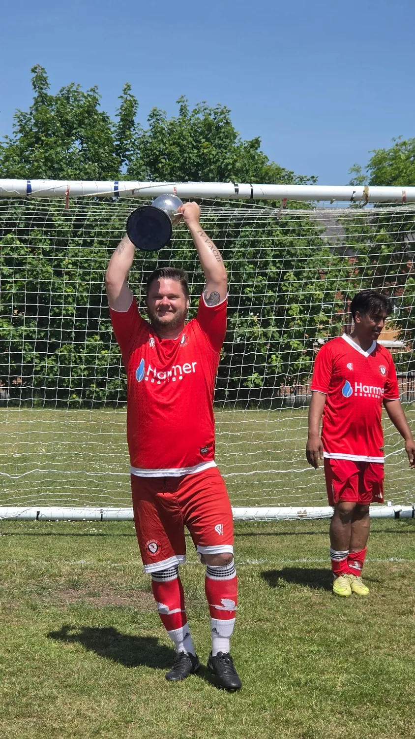 Heron United player lifting the trophy above his head