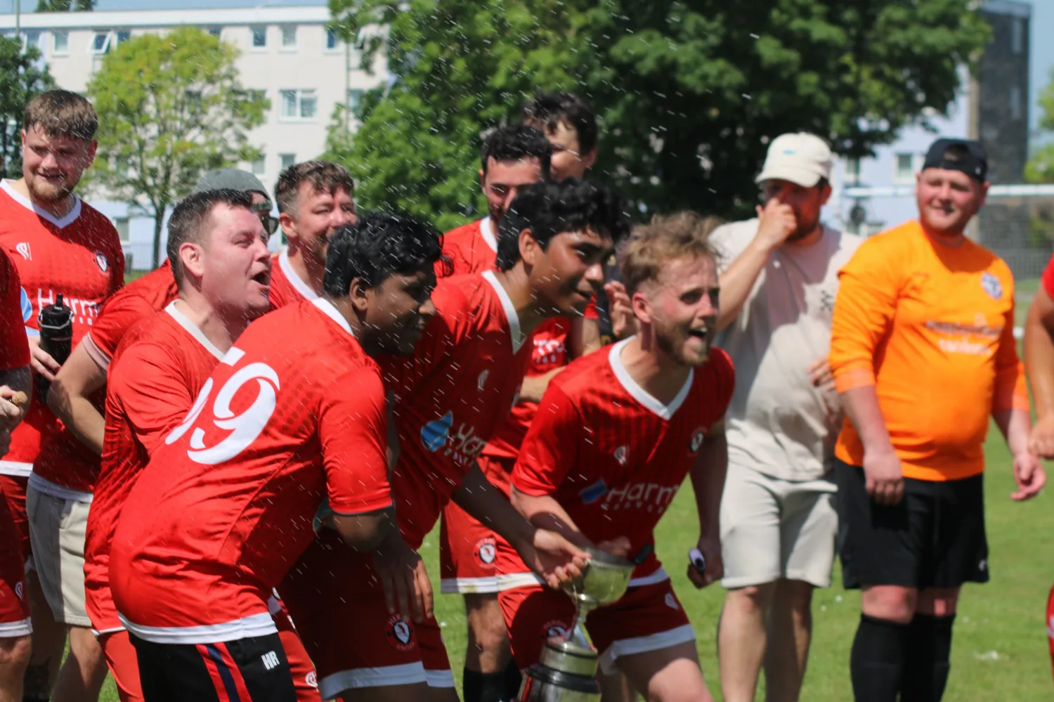 Heron United players celebrating with spray and the trophy